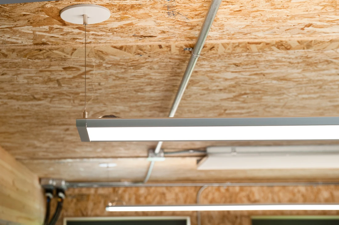 Inside, the classroom looks almost unfinished. The chipboard walls are visible, as are all the ducts, cables, conduits and structural supports, allowing the children to see firsthand how the building works
