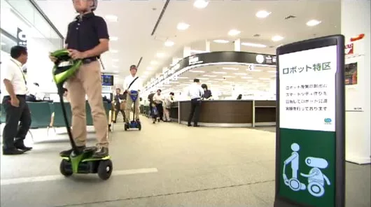 Toyota Winglet riders pass by a sign showing the area is part of Tsukuba city's Robot Experimental Zone