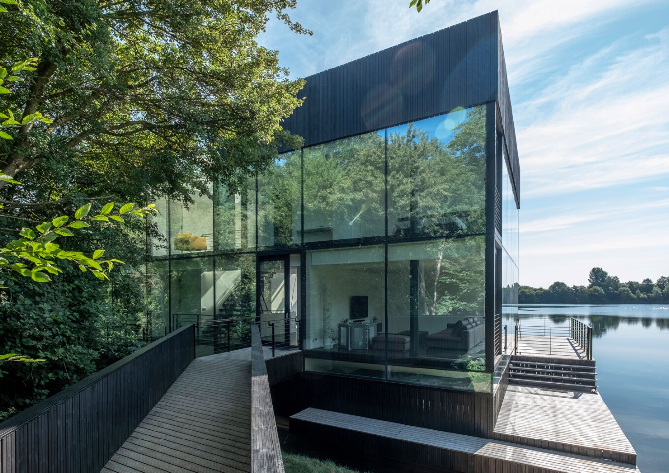 The Glass Villa on the lake is connected to a main road with a wooden footbridge