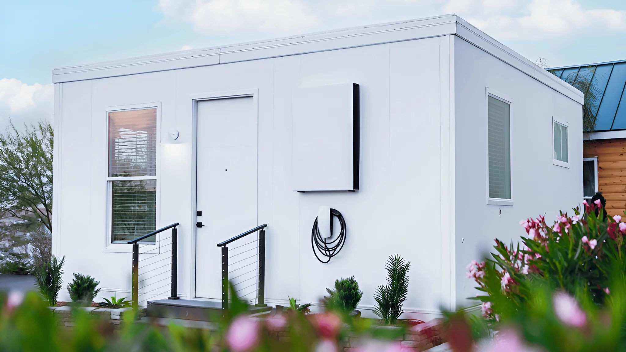 The exterior of the Boxabl Casita tiny home, shown with a Tesla charger mounted to the outside