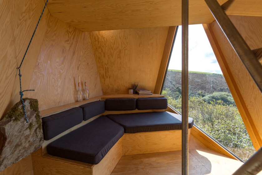 Each cabin accommodates up to two guests and features a cozy lounge with log fire and large triangular window overlooking the serene landscape