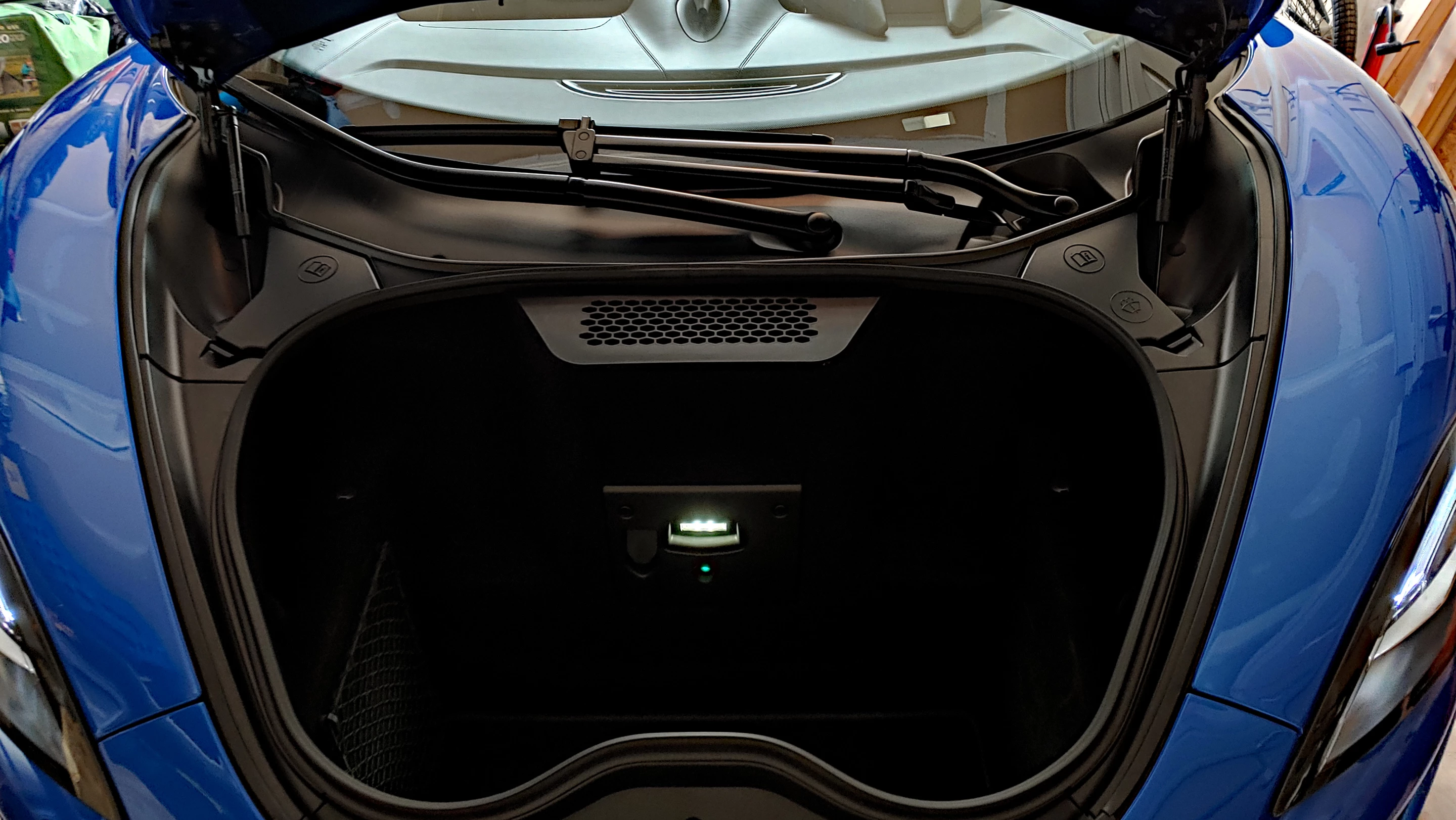The McLaren 570S' frunk has room for a couple of carry-on bags and (next to the LED light) a plug for battery maintenance when parked for long periods