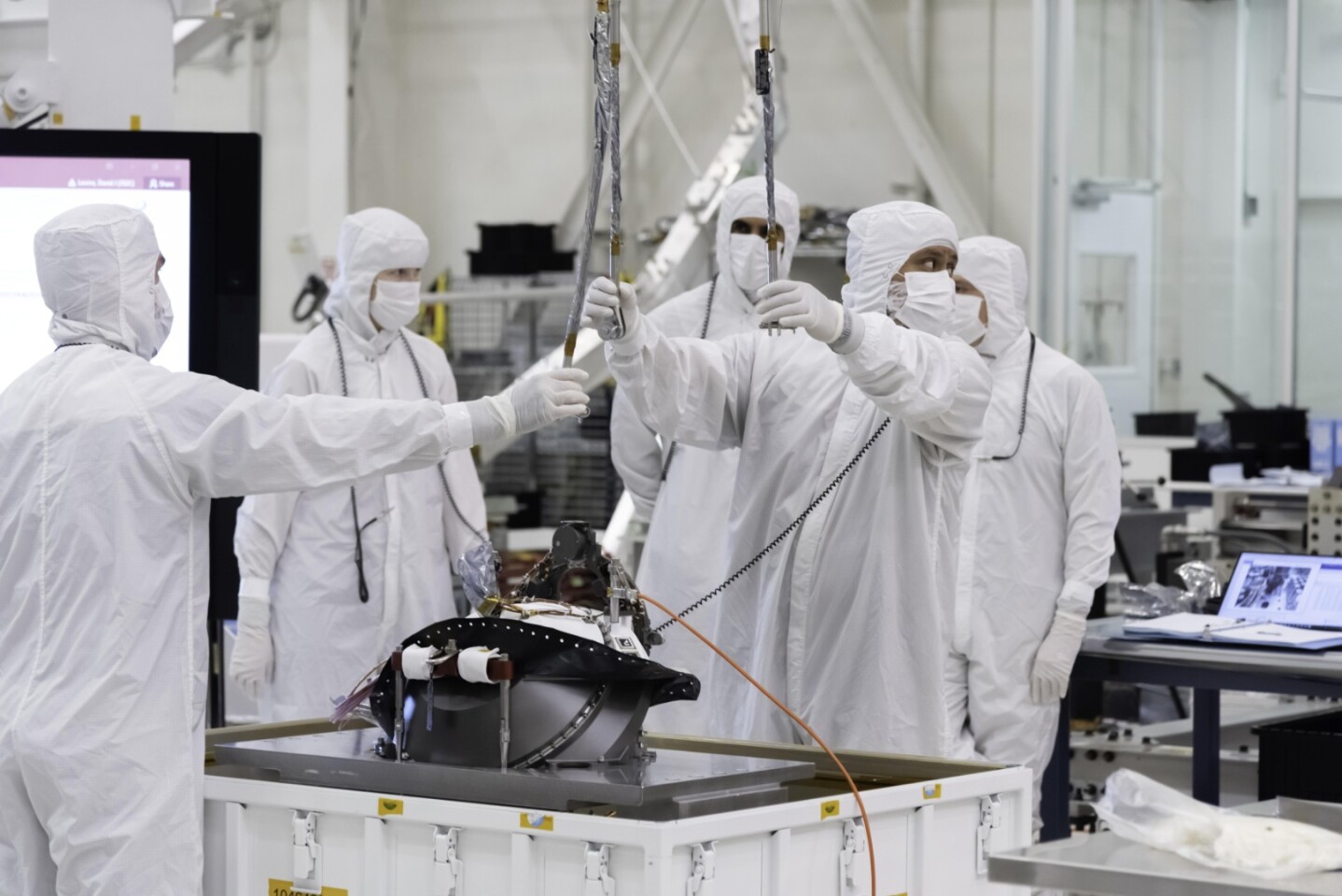 Engineers at NASA's Jet Propulsion Laboratory lift the Mars 2020 rover's bit carousel out of its storage container