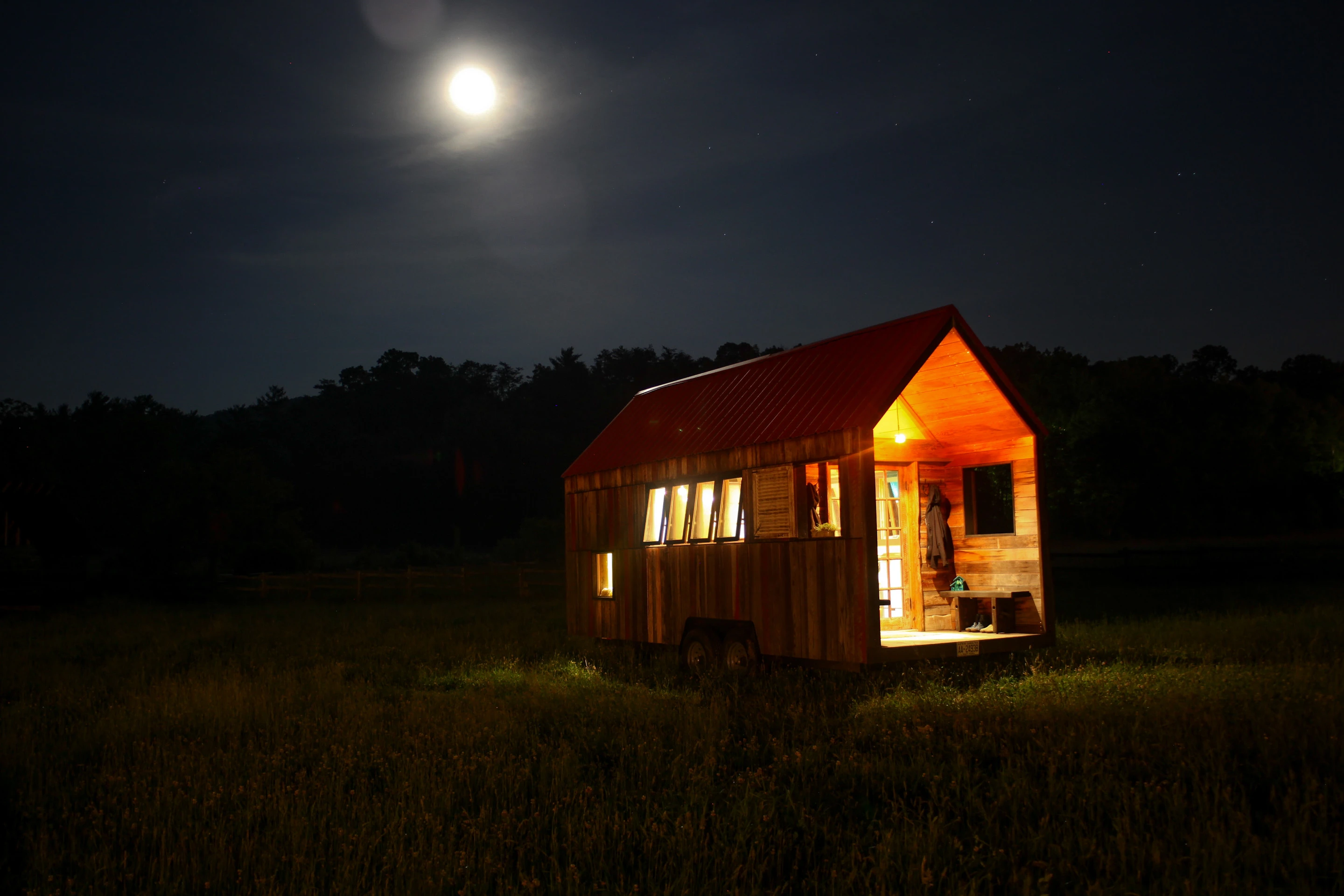 The home features a trailer base, frame and a colorful rustic exterior made from local and up-cycled hardwoods