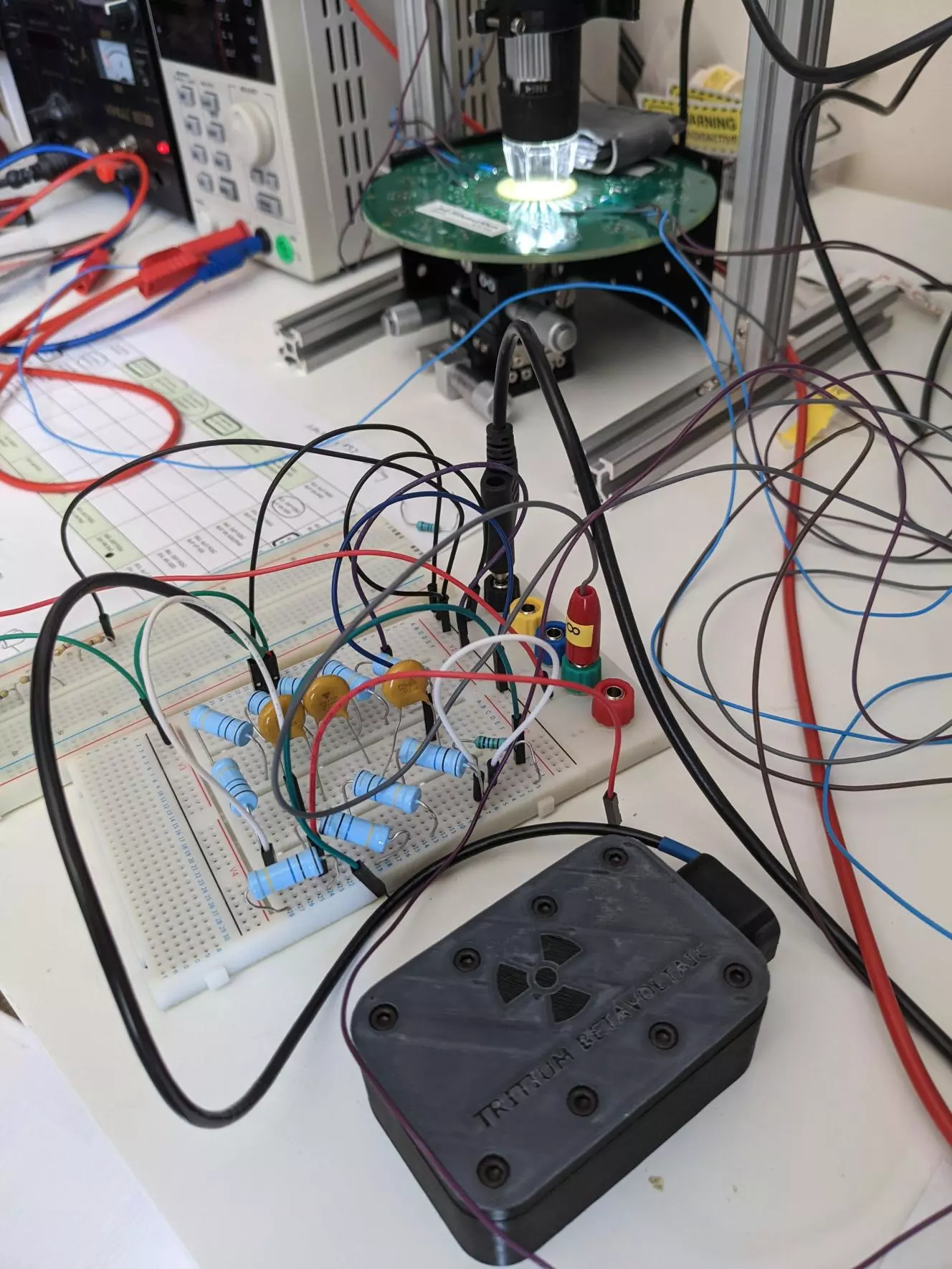 Arkenlight's early stage tritium beta-battery, in the black box, powers an Axorus artificial neuron, in the circle of light, in a proof-of-concept both companies hope will lead to a medical-grade implant