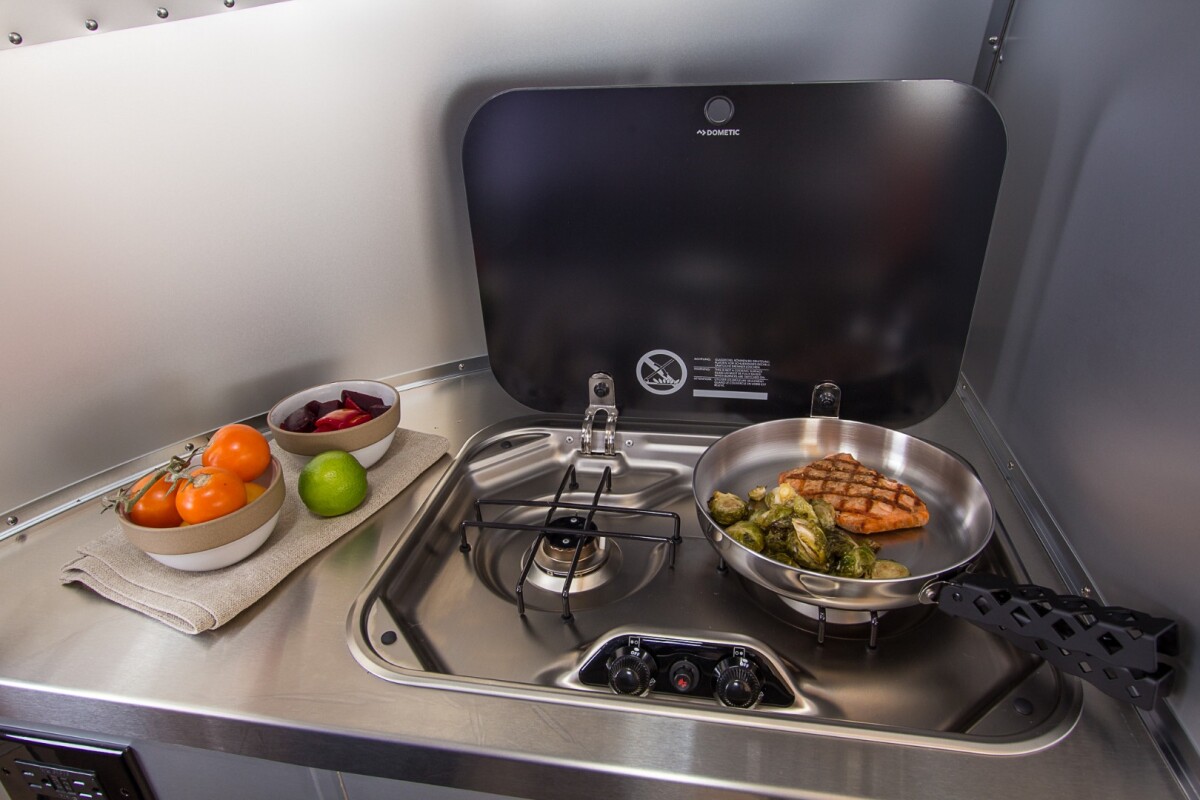 The kitchen includes stainless steel counters and sink and a dual-burner cooktop