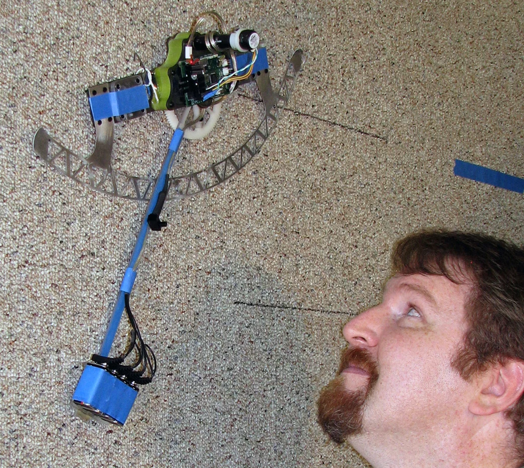 William Provancher watches as the efficient climbing robot he and colleagues developed scales a carpeted wall (Image: Mark Fehlberg, The University of Utah)