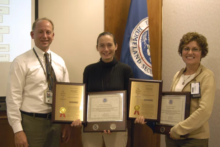 Adam Hutter, Director of NUSTL, presents Cecilia Murtagh (center) and Gladys Klemic with plaques commemorating Homeland Security's first patent, for the Citizen's Dosimeter (Photo: Jenny May)