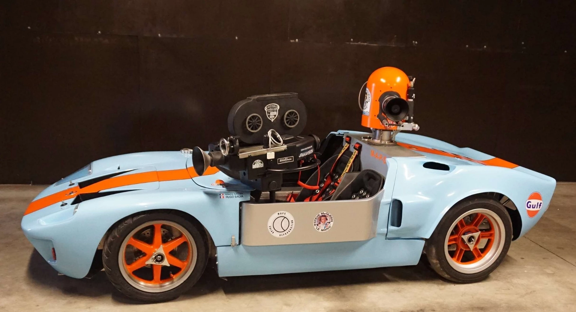 When Steve McQueen's Solar Productions was filming the 1971 film Le Mans, one of the camera cars was a Ford GT 40 in Gulf colors which was transformed into a "barchetta" and equipped with cameras. The car subsequently was transformed back into a complete GT40 and became the most expensive movie car ever to sell at auction (fetching US$11,000,000 at an RM Auctions sale at Pebble Beach in 2012) with a prominent spot in the top 100 most expensive cars of all time. This is a tribute 2/3 scale junior car with real movie cameras and it fetched $39,821 (€32,500) ... truth is stranger than fiction.