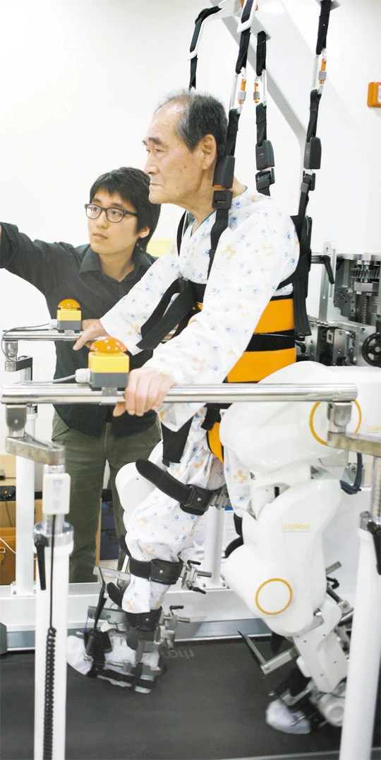 A physical therapist works with a patient walking with the Walkbot gait training system (Photo: Daejonilbo.com)