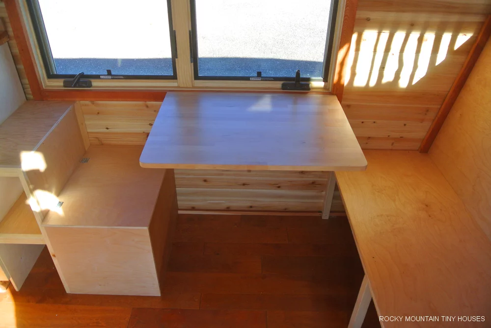 The dining area features folding seating that reveals storage space, in addition to a fold-up table (Photo: Rocky Mountain Tiny Houses)
