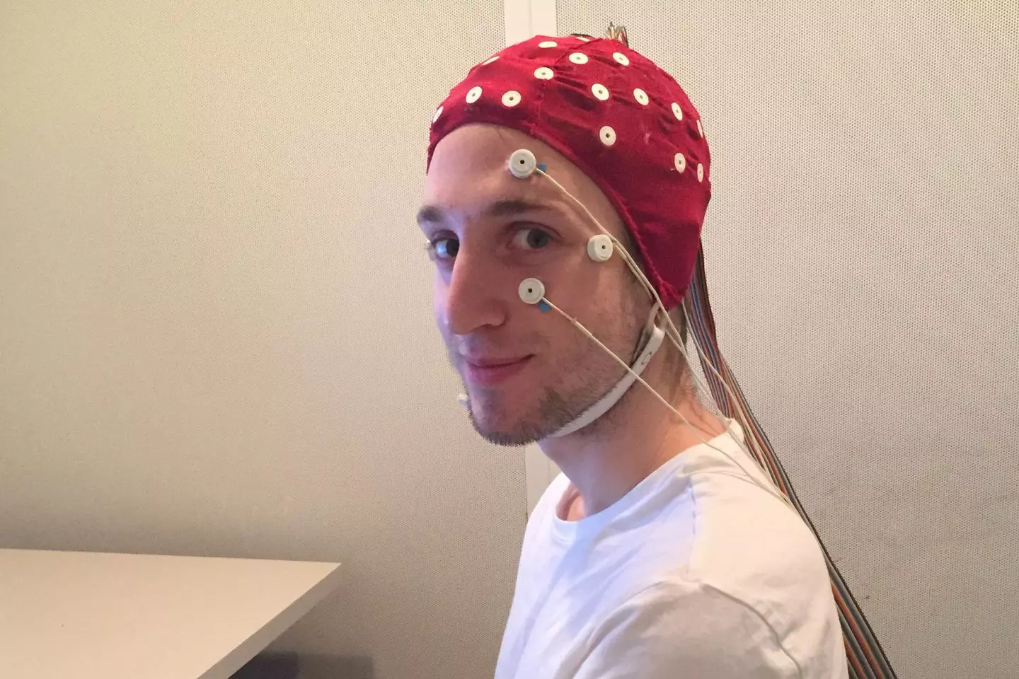 A subject in a full EEG rig just before a sleep session in the lab. The electrodes on his face will detect the movement of his eyes as he sleeps.