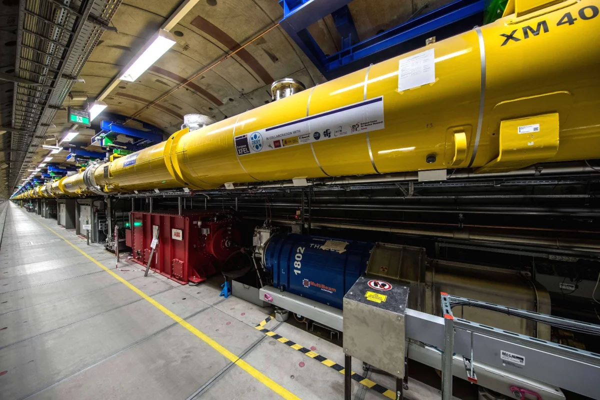 View into the 2.1-km long accelerator tunnel of the European XFEL with the yellow superconducting accelerator modules hanging from the ceiling