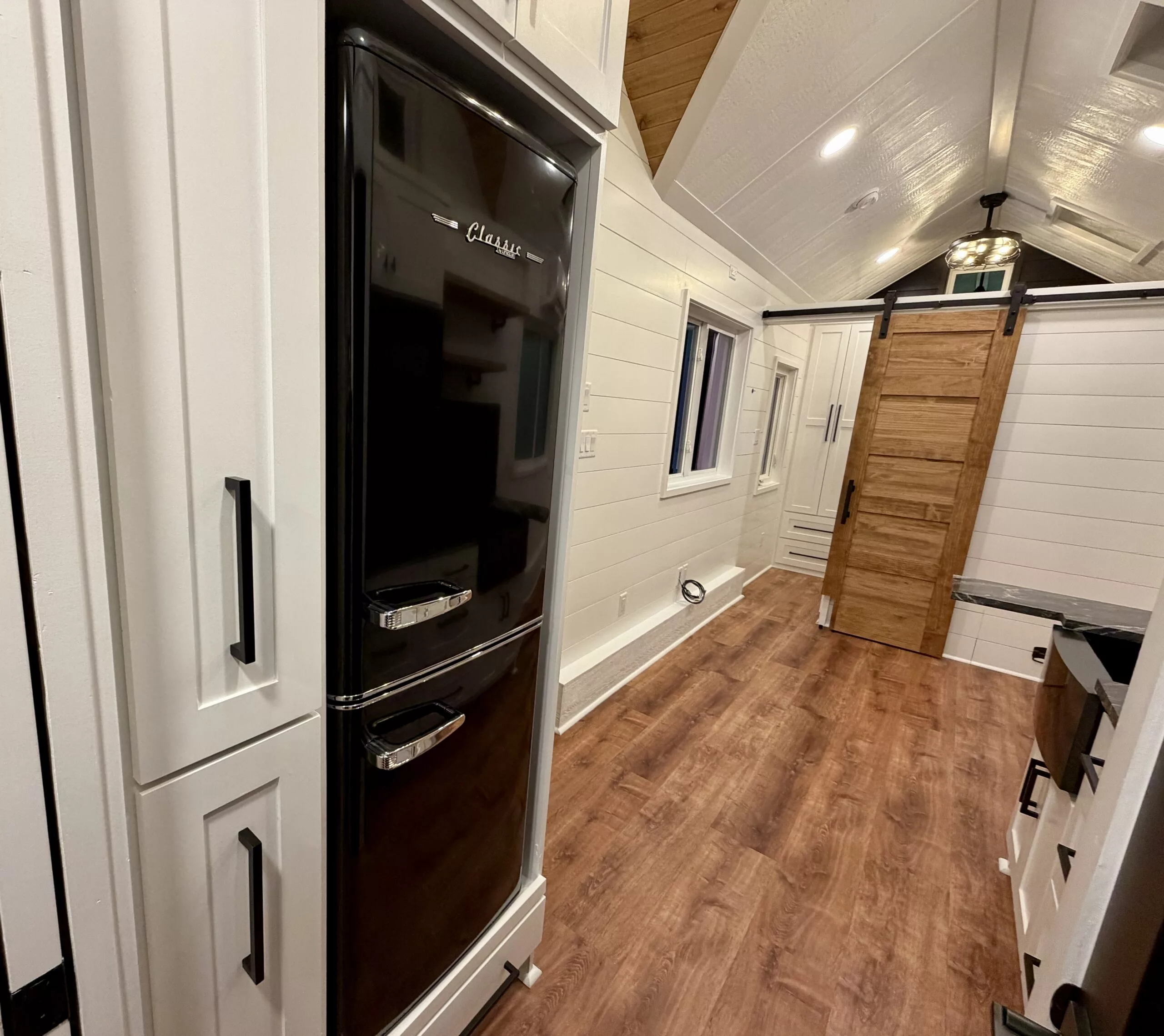 The Betty tiny house's downstairs bedroom is reached by a sliding barn-style door
