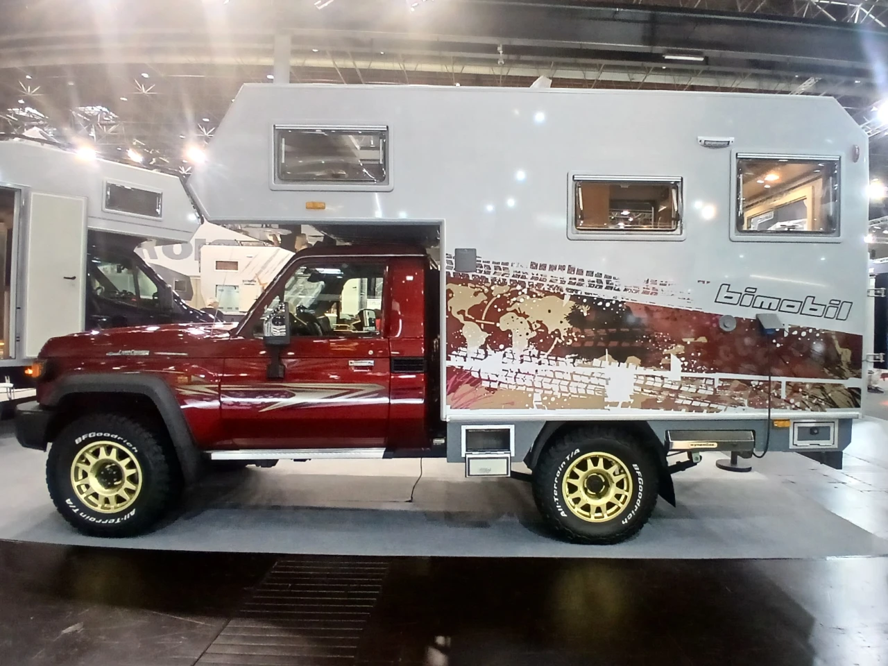 The deep red of the cab, the gold graphics and wheels, and the tire-treaded world map of the Bimobil cabin give this EX 270 show RV its unique look