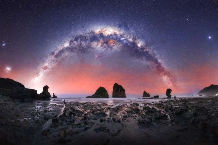 The Rocks. The bright galaxy sets over ancient sea stacks and exposed reefs at Motukiekie, along the West Coast of the South Island of New Zealand