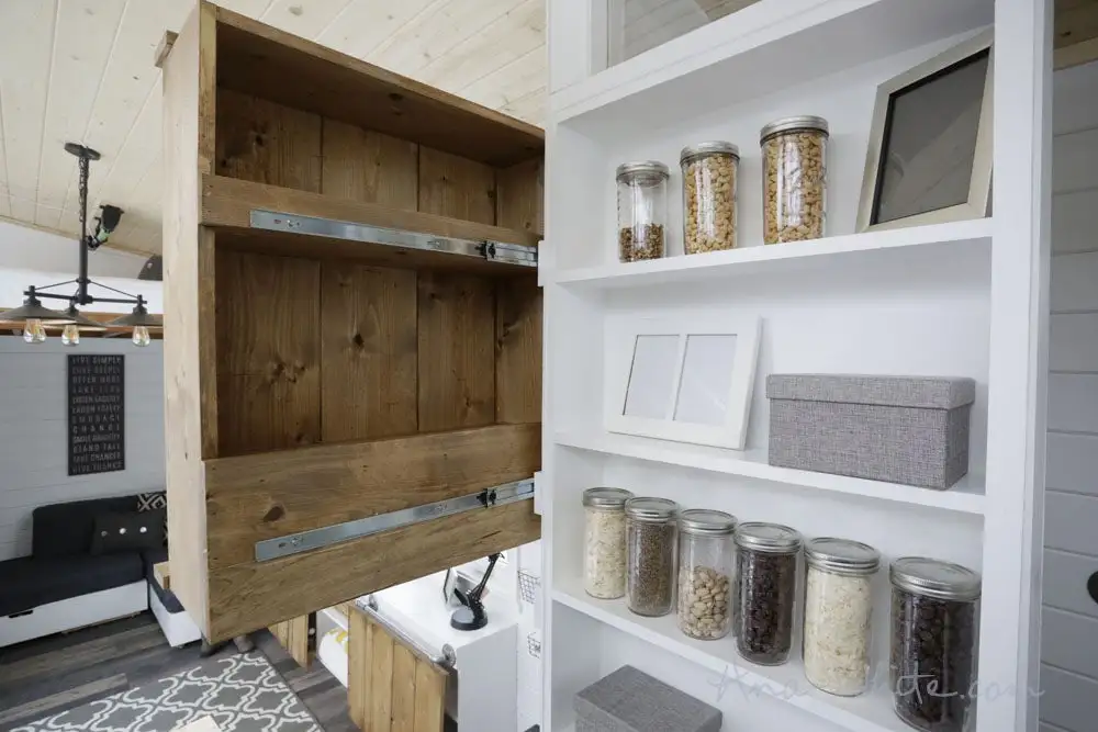 The Open Concept Rustic Modern Tiny House's bathroom includes a movable clothes closet on a track