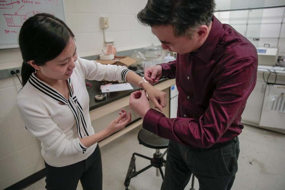 A University of Wisconsin-Madison researchers fits a smart bandage around the wrist of graduate student Yin Long