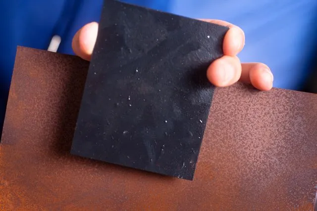 A piece of steel treated with the graphene varnish, in front of an untreated sample