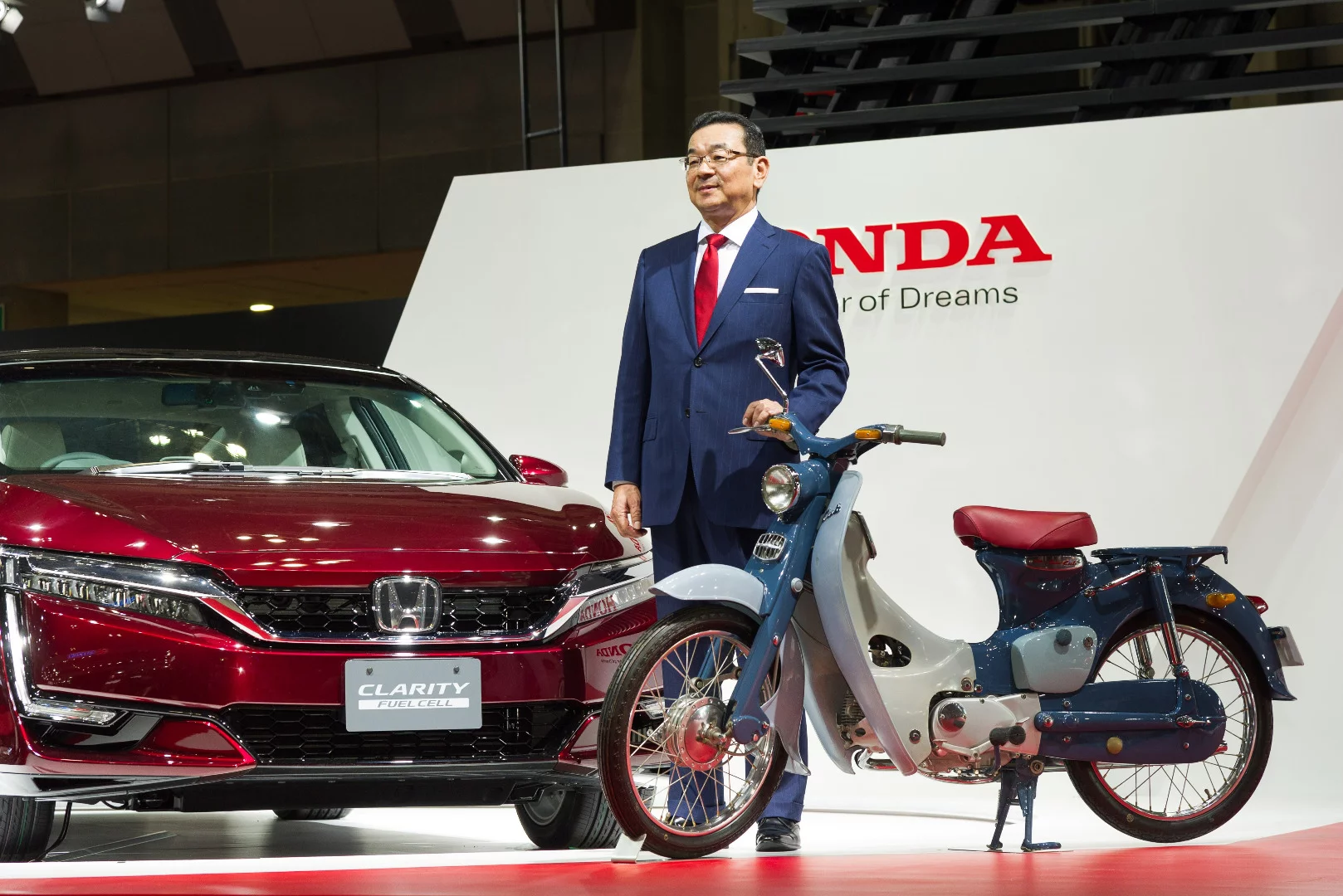 Honda Motor Co. President and CEO, Takahiro Hachigo, standing next to an original 1958 Super Cub