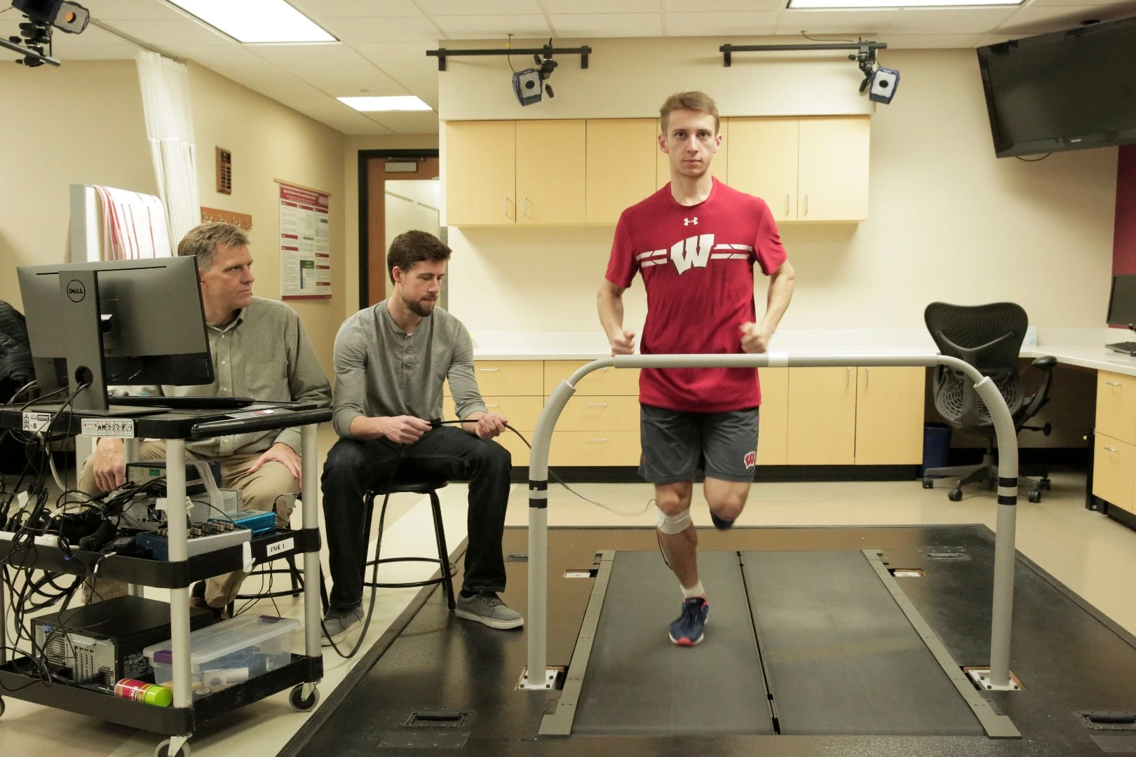 Darryl Thelen (far left) and Jack Martin measure tension in student Alexander Teague's tendon