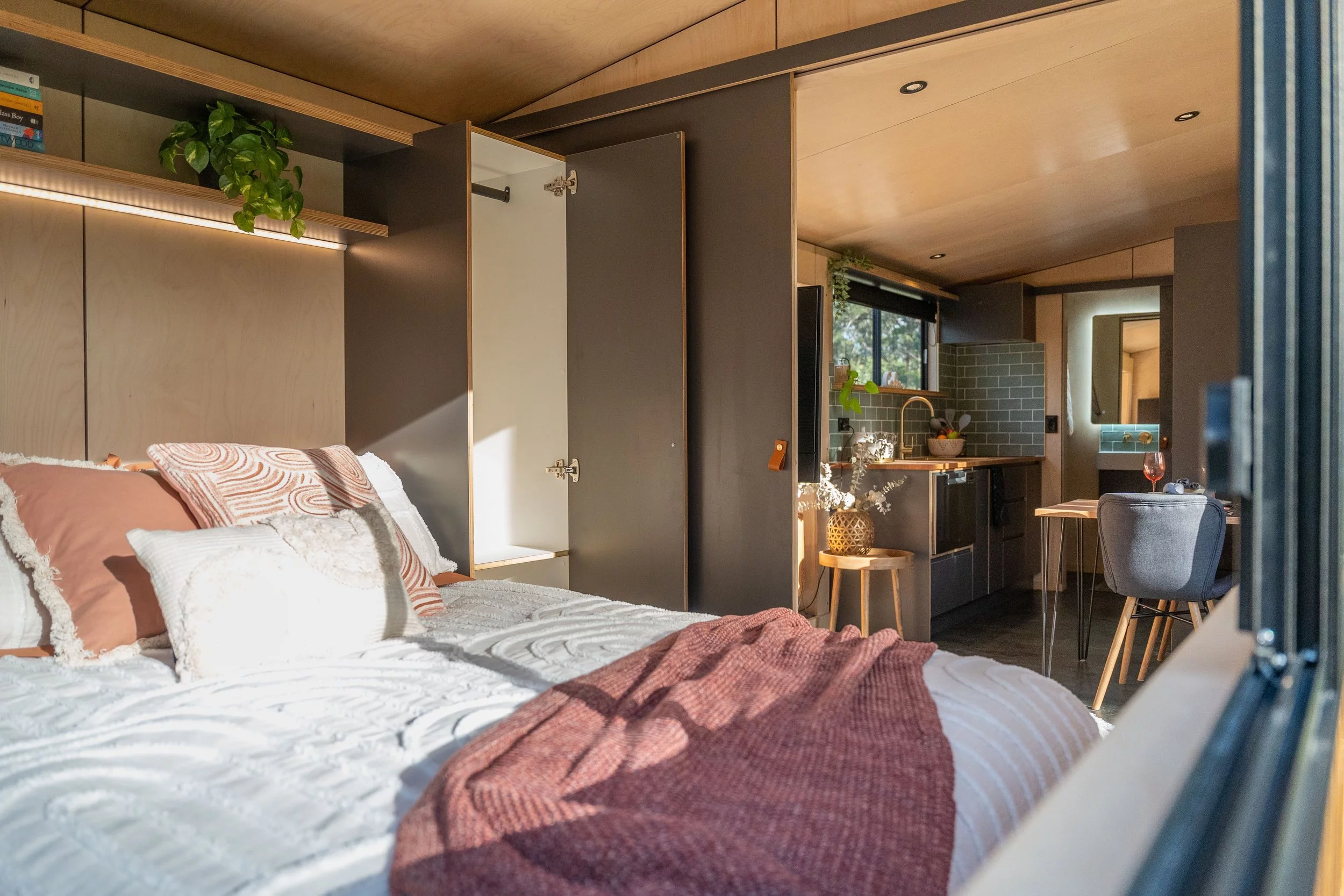 The Luna tiny house's bedroom is accessed by sliding doors from the kitchen