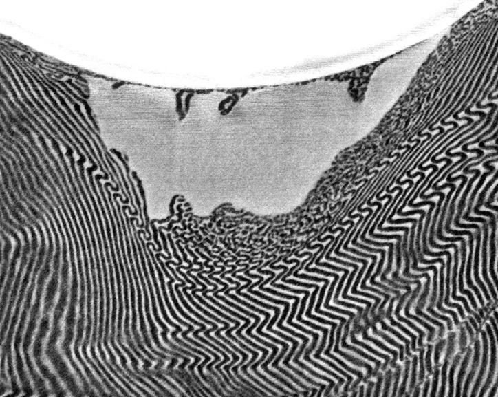 An electron-microscope image shows a cross-section of a layered polymer and the crater left by a glass bead in an edge-on impact (Photo: Thomas Lab, Rice University)