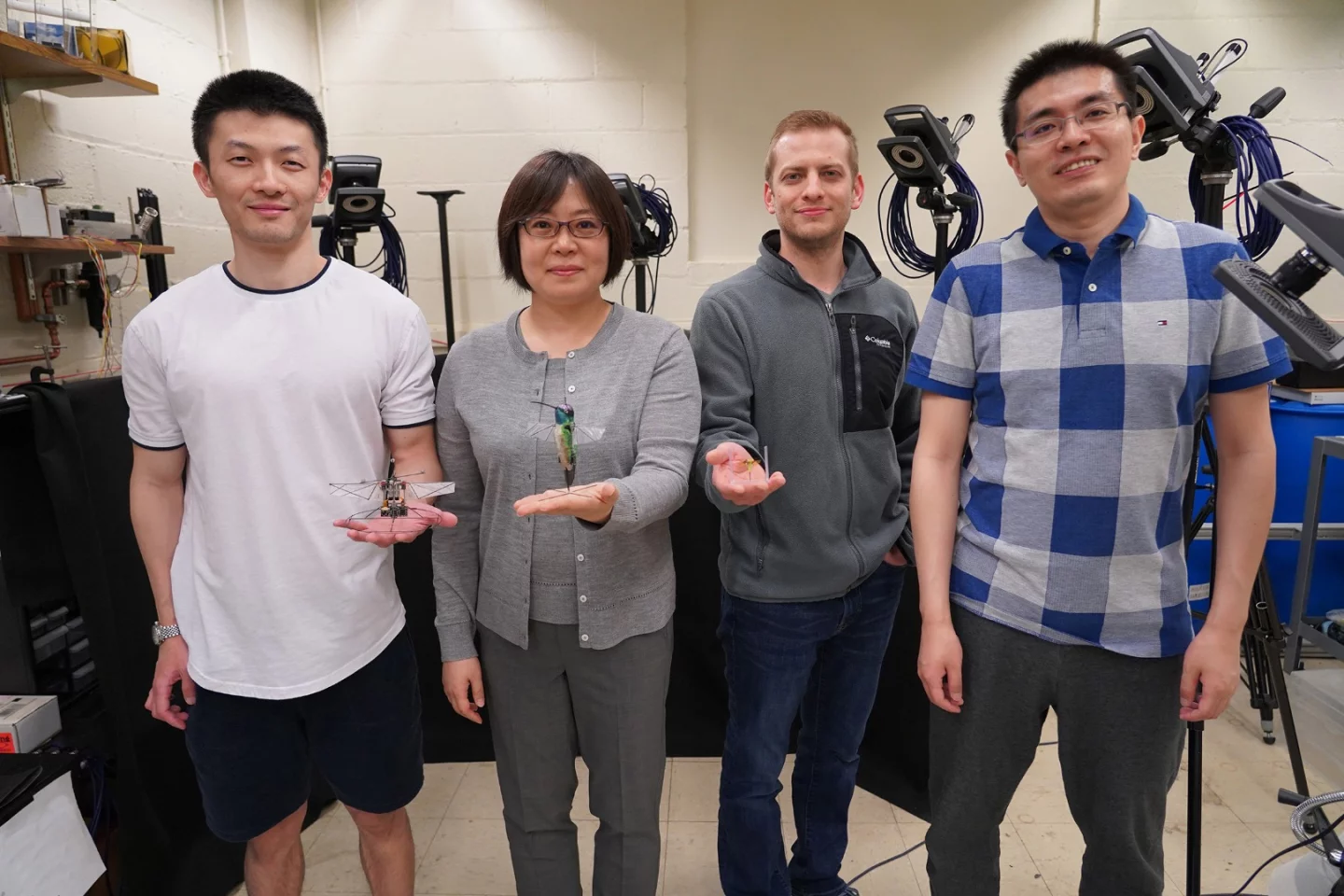 The researchers on the team (from left: Fan Fei, Xinyan Deng, Jesse Roll and Zhan Tu), with the robotic hummingbird and insects