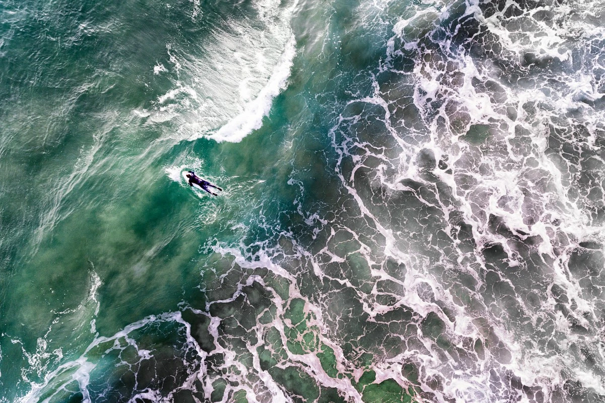 Surfer heads for the swell off the coast of Portugal
