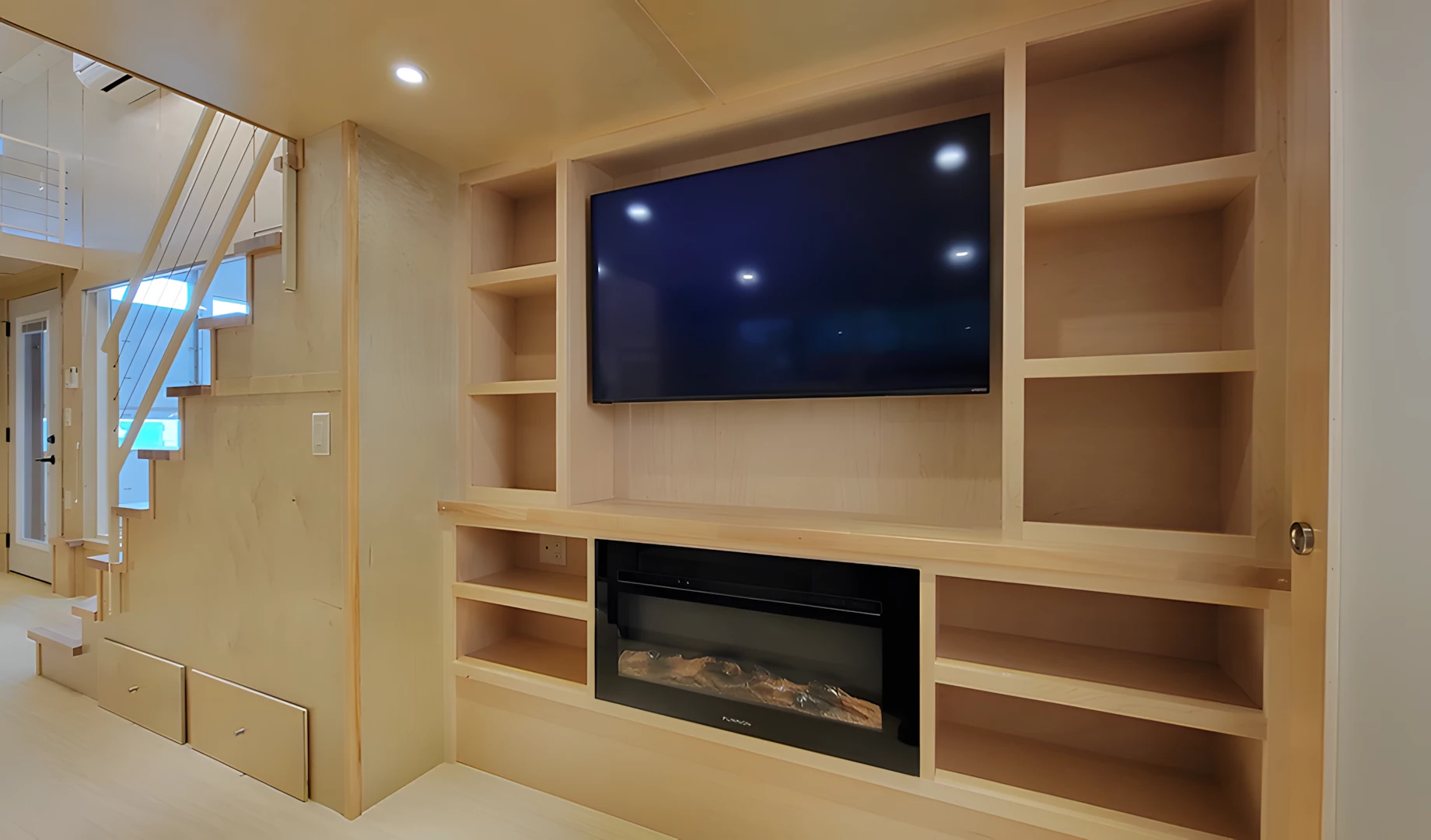 The Ultimate tiny house's living room includes a TV and an electric fireplace