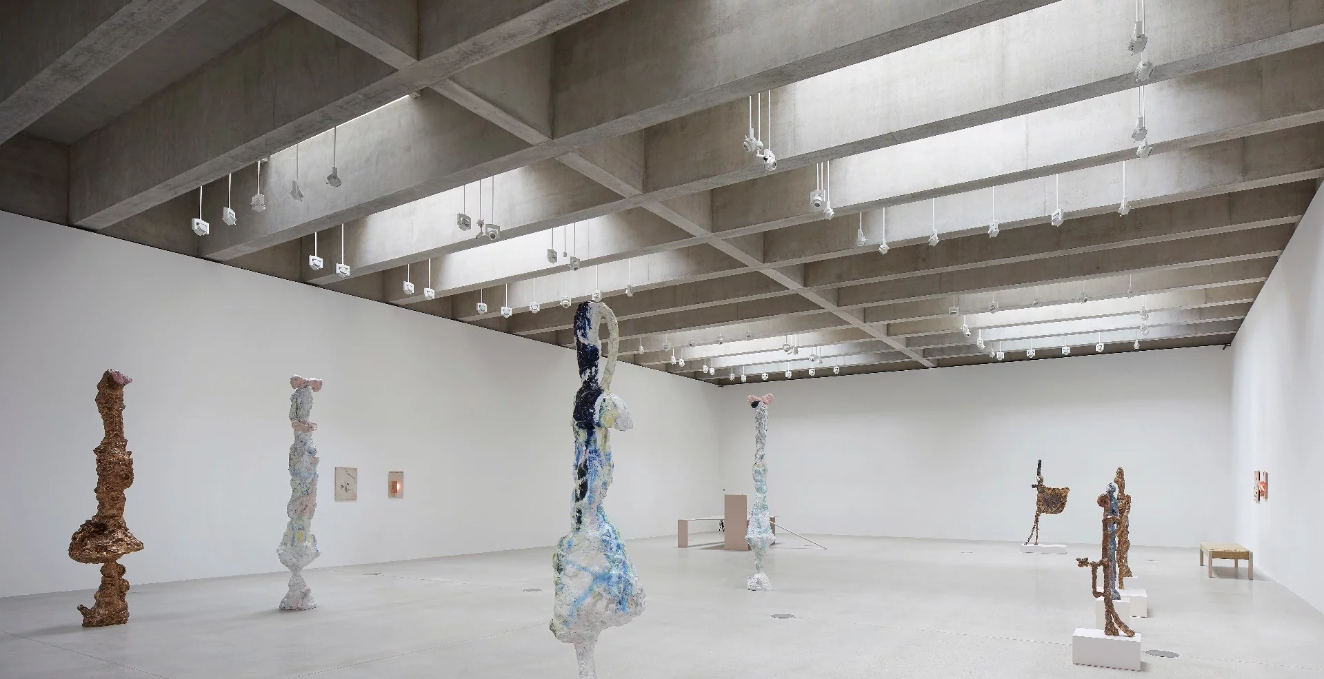 The new gallery spaces at New Tate St Ives are lit from the top down, where sunlight pours through the glass and granite roof built into the hillside and supported by exposed concrete beams