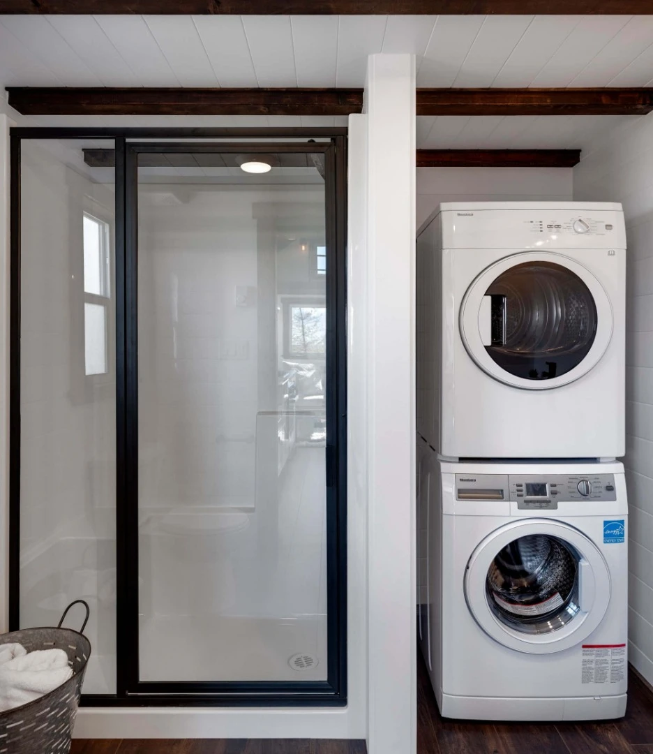 The bathroom/laundry with full 4-ft (1.2-m) vinyl set shower, basin, traditional flushing toilet and stacked washing machine and dryer