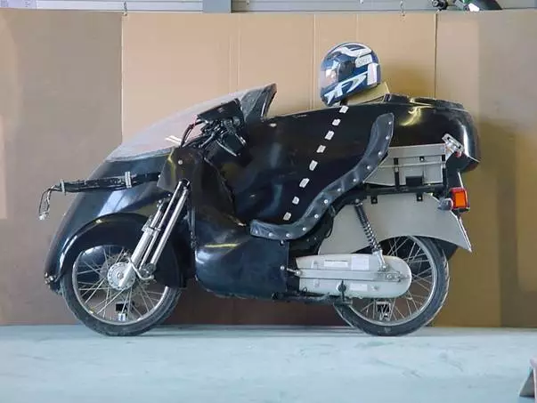 The streamlined casing sits behind the modified scooter, showing how the finished vehicle's parts come together