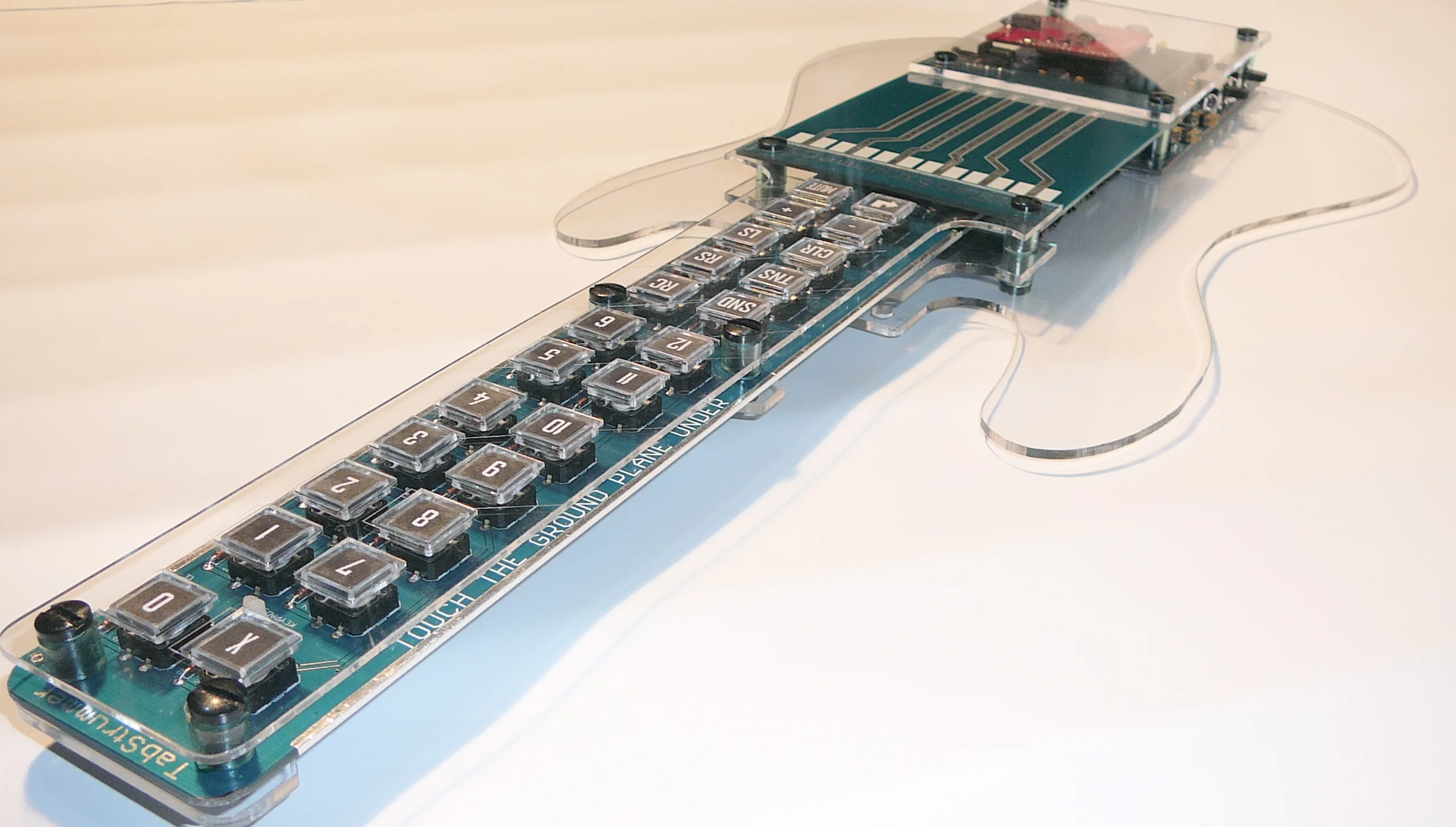 The guitar-shaped Tabstrummer programmable MIDI controller allows users to create and register guitar chords to buttons on the neck and strum songs via PCB strings