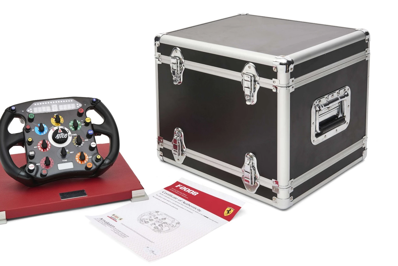 A limited edition (number 134 of 250) Ferrari F2008 Formula One steering wheel mounted on a red leather base, sold with a carrying case and a complete manual explaining the functions of the wheel. The F2008 designation indicates that this is identical to the steering wheels used in the Ferrari F2008 cars driven by Kimi Räikkönen and Felipe Massa during the 2008 season. Sold for $2,156 (€1,760)