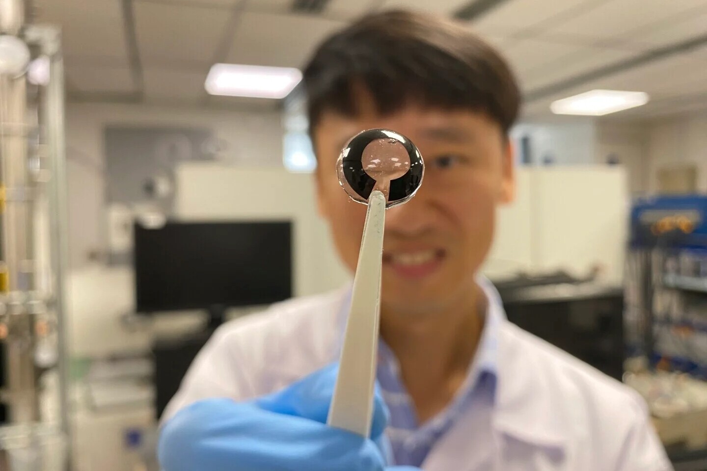 Assoc. Prof. Lee Seok Woo with a contact lens equipped with the prototype battery (black)