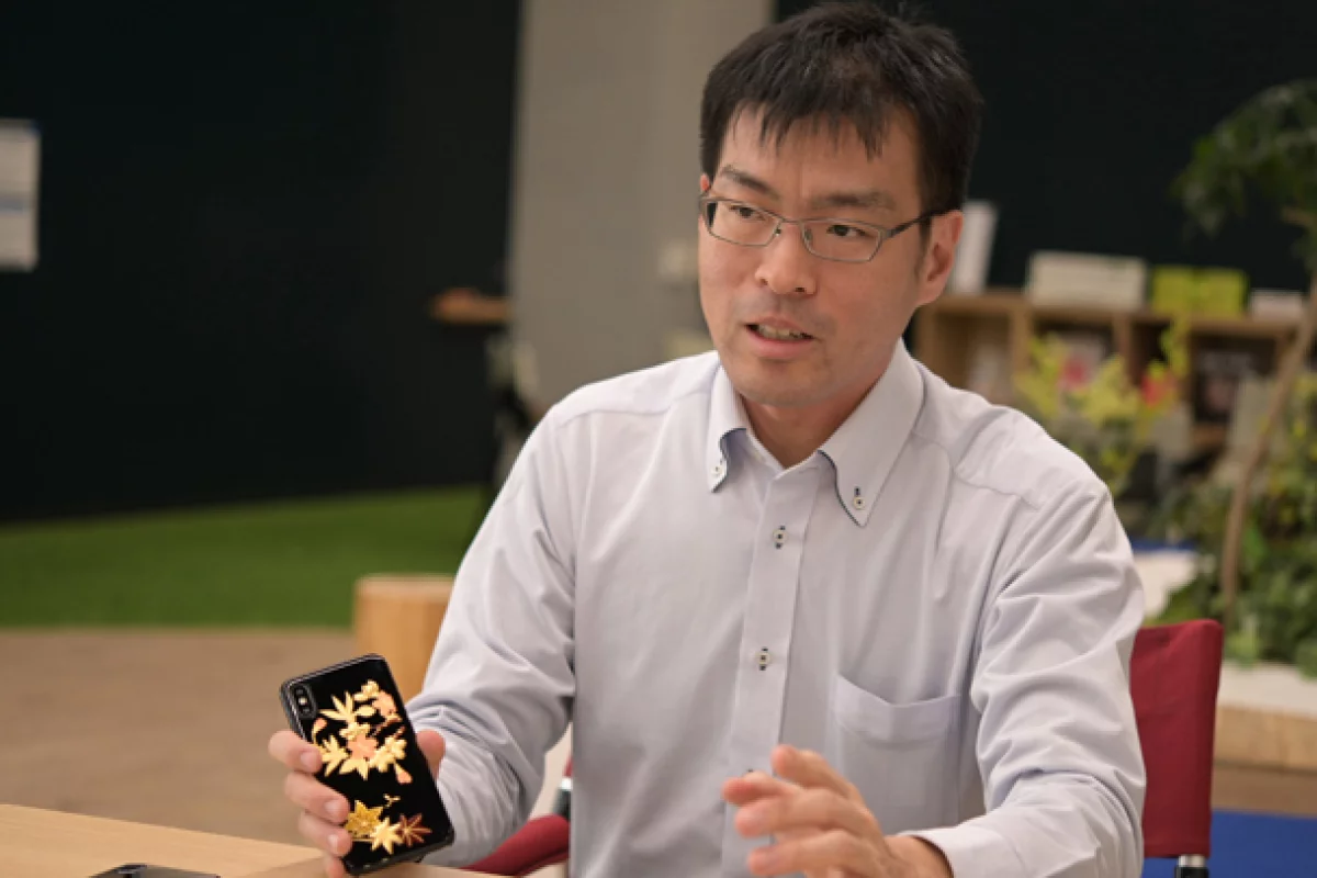 Shukichi Tanaka, one of the NEC researchers with the new bioplastic used in a smartphone