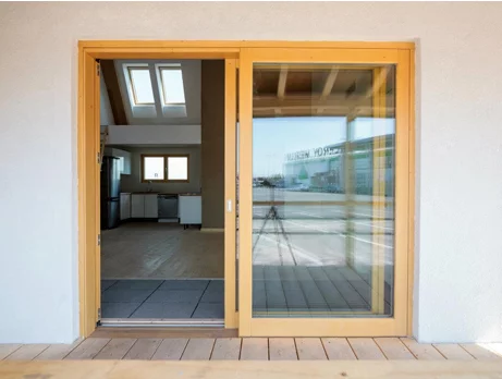 The southern side features large open windows and sliding doors that open out onto the shaded balcony terrace with overhead veranda