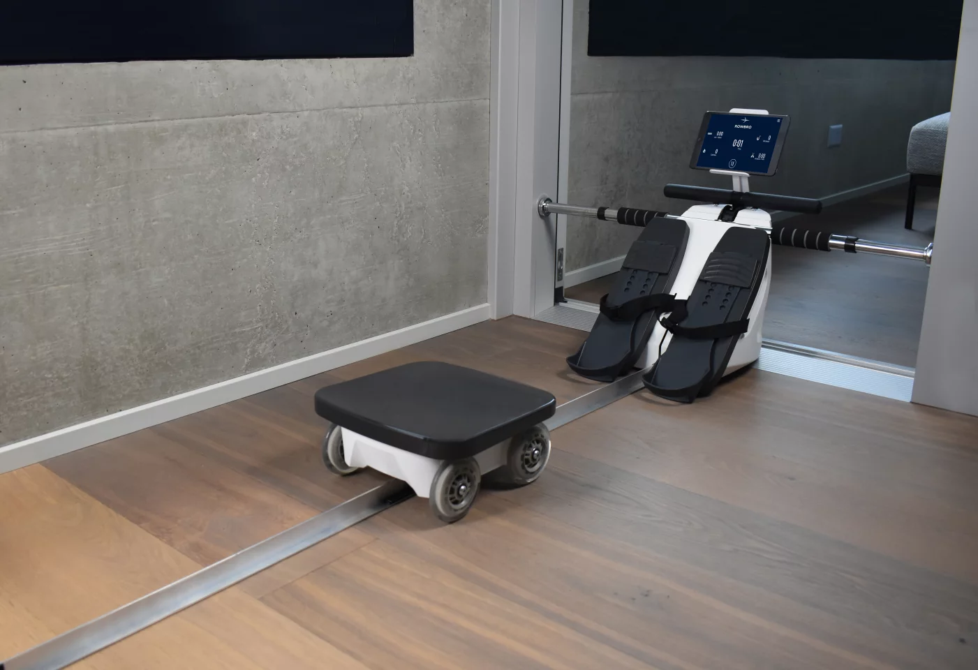 The RowBro mounts within a door frame, and its seat rolls along the floor