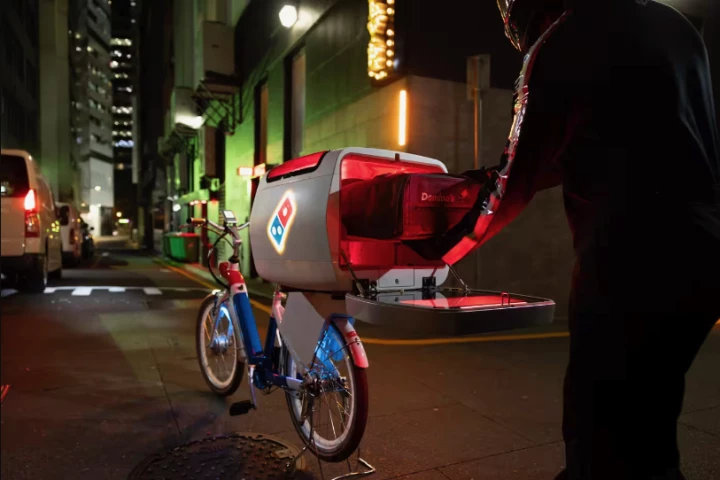 A Domino's Pizza delivery cyclist accesses the dXb's Pizza Pod