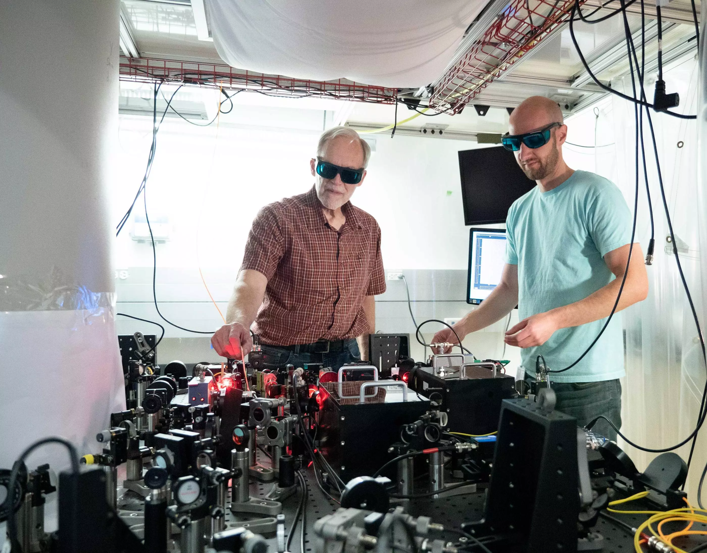 NIST physicists John Bollinger (left) and Matt Affolter (right) with the optics system used to trap and study beryllium ions