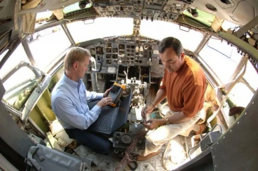 Mike Dinallo and Larry Schneider prepare to employ the PASD diagnostic on a wiring bundle in the cockpit of a retired Boeing 737. (Photo by Randy Montoya)