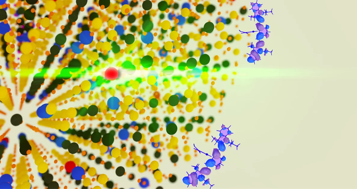 A close-up artist's rendition of an upconverting nanoparticle: after the nanoparticle has absorbed infrared light, an erbium atom (red) emits it as visible green light, and the blue and purple molecules are dyes that improve the function