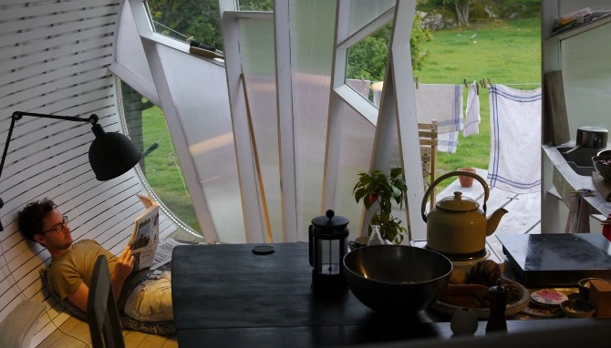 Integrated within the small space is a central kitchen, dining and living area, hallway, elevated sleeping quarters and outdoor terrace