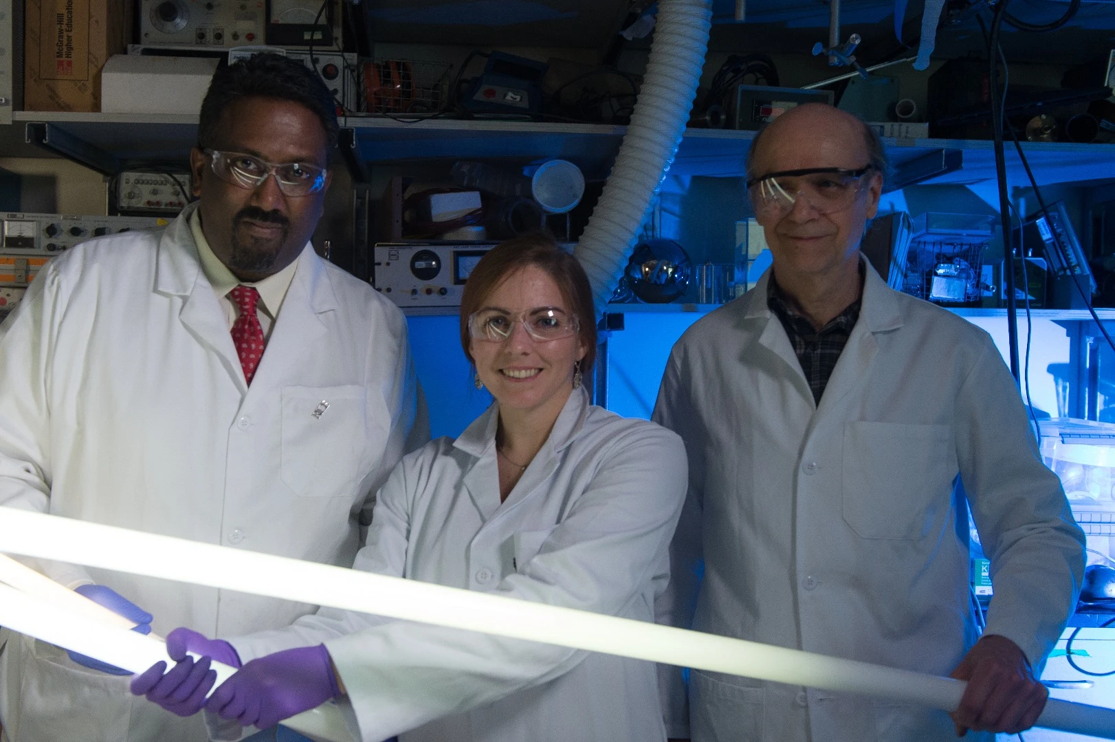 Rice University chemist Paul Cherukuri, left, Texas A&M graduate student Lindsey Bornhoeft, center, and Rice research scientist Carter Kittrell holding fluorescent tubes powered by the Tesla coil electric field