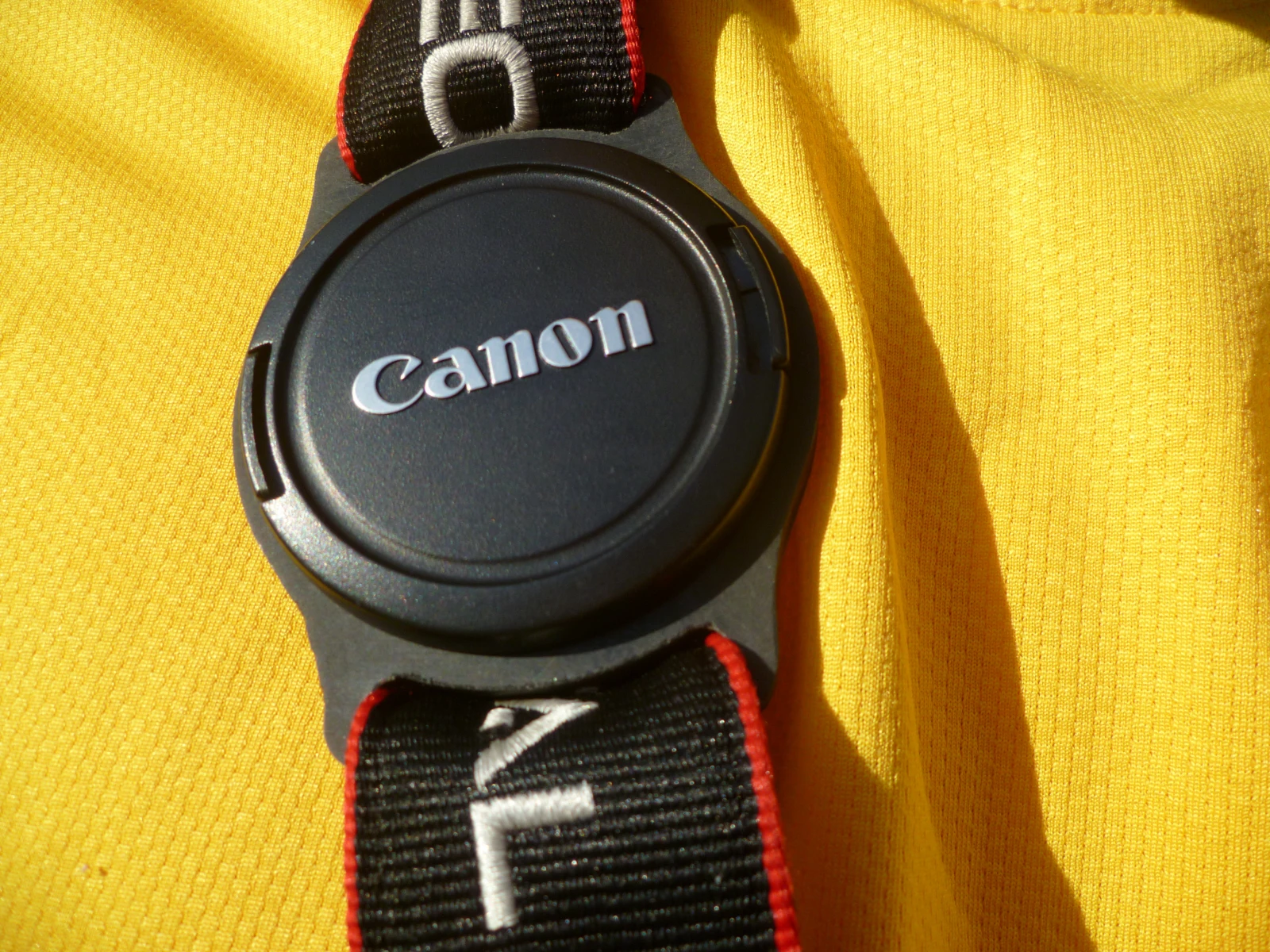 The camera strap slots through the buckle holes on either side of the circular recess of the holder