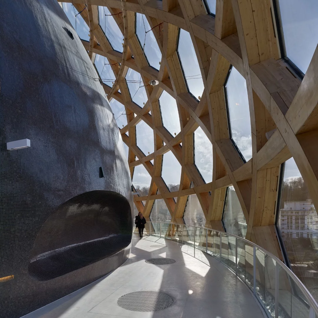 The glazed auditorium is supported by a shell of timber laminate made from woven spruce wood