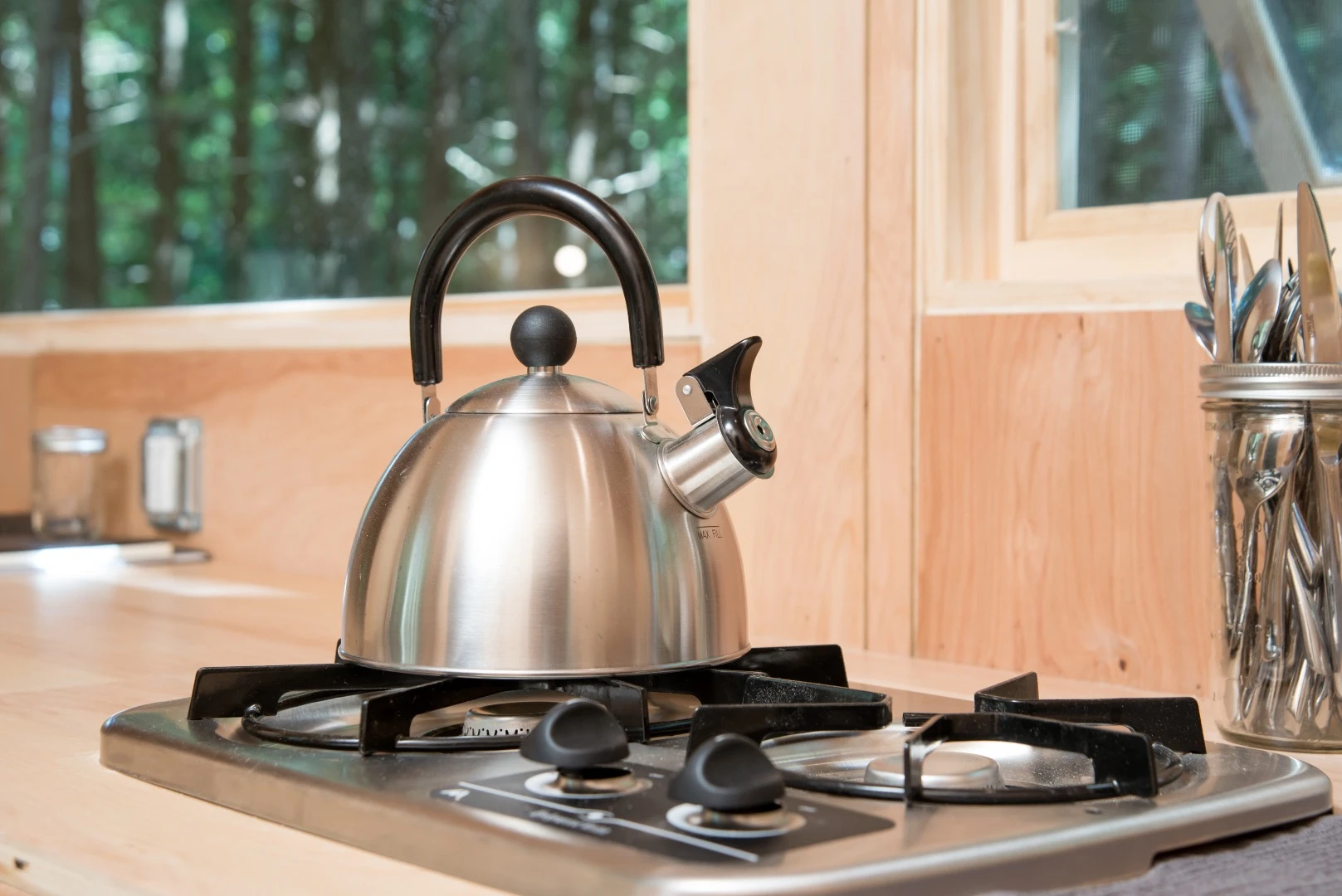 The small kitchenette features a two-burner propane stove, vintage style Coleman cooler, and a sink