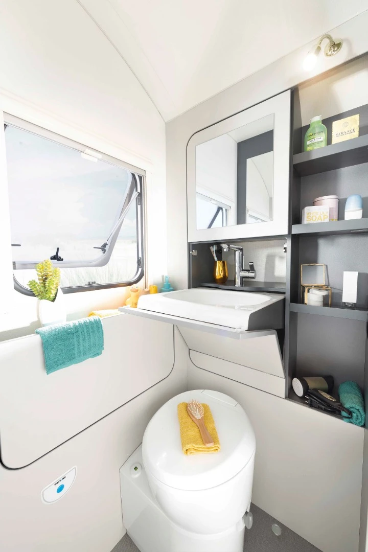 The corner bathroom includes a toilet and fold-down sink, but does away with the interior shower, leaving folks to pull the faucet out the window if they want a shower