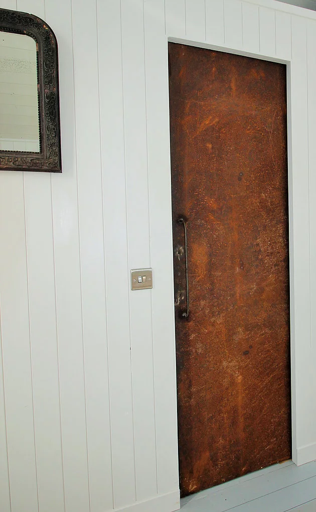 The bathroom is accessed via a rusted door